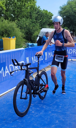 A triathlete running with his bike into transition