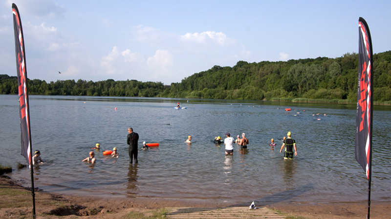 lake entrance with club flags and swimmers in the water