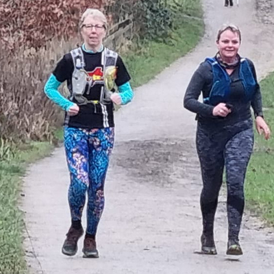 Two women running side by side on a country path