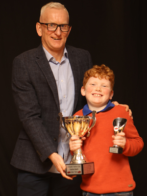 A man presenting a trophy to a young boy
