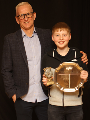A man presenting a trophy to a boy