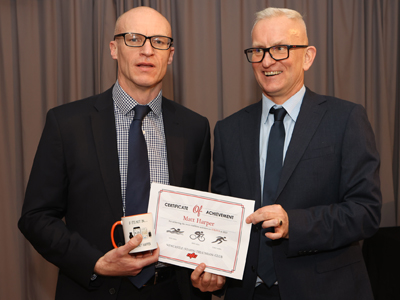 Two men, one holding a mug and certificate